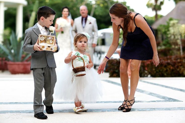 Flower girl gets a hand from a bridesmaid as she makes her way up the wedding aisle Flower girl getting some help up the aisle