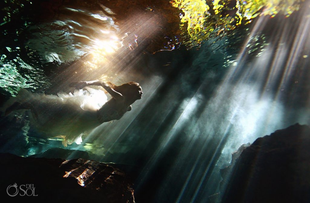 This bride efforlessly glides through beautiful streaks of light making their way through Cenotes openings. 1 bride going through the cenotes