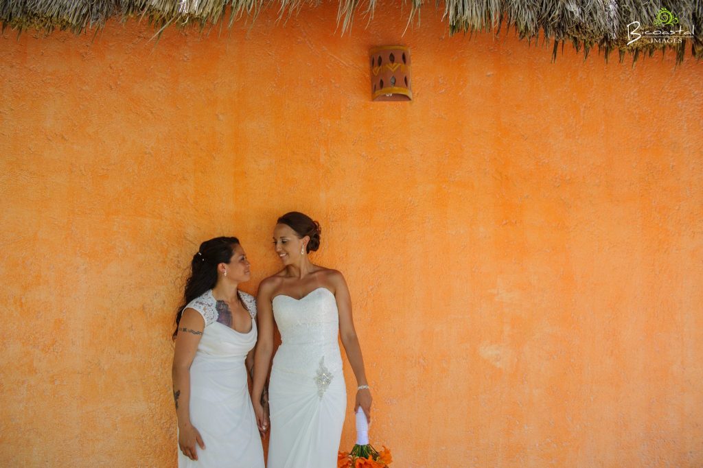 1 couple standing against an orange background. 