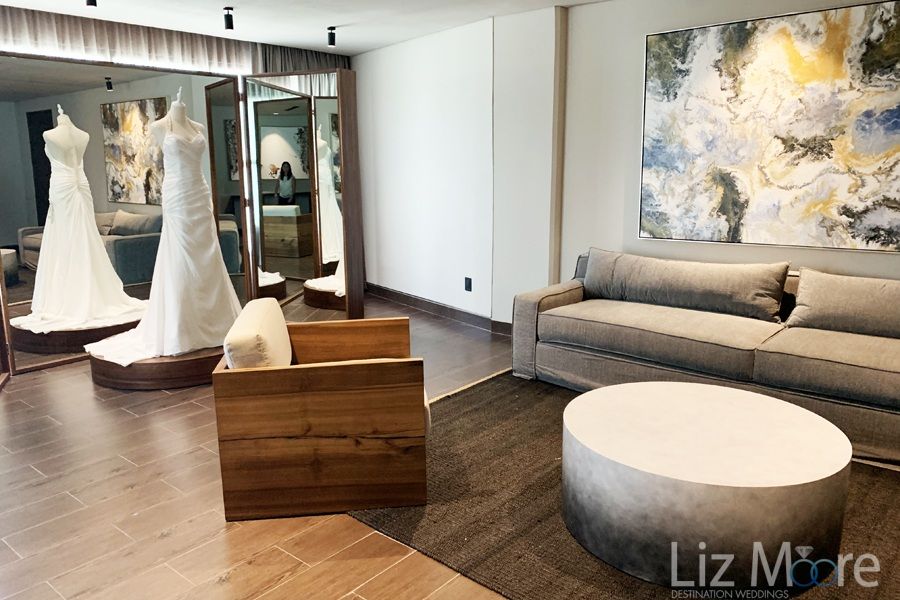 bridal room With a beautiful soft beige couch chairs hardwood floors and wedding dress