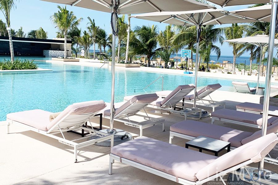 lounge chairs by main pool In pink With umbrellas overhead