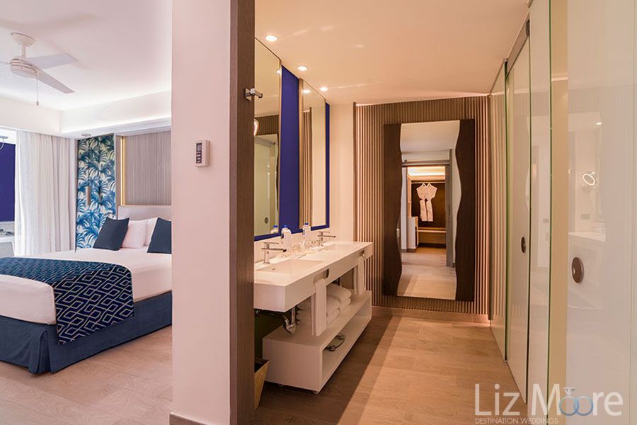 privilege suite With double vanity sinks blue bedspread and Entrance into Bathroom