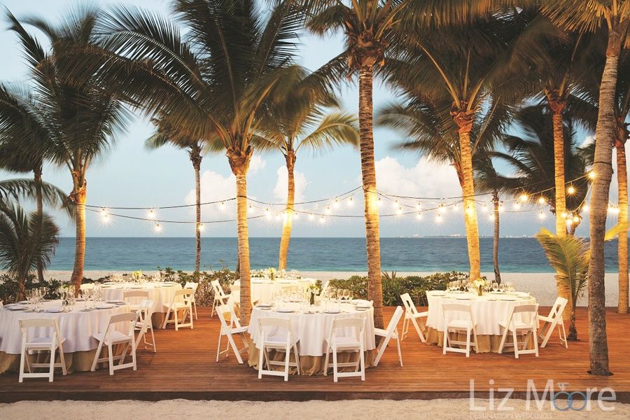 beach wedding reception With soft tiki lighting and palm trees by the beach and ocean