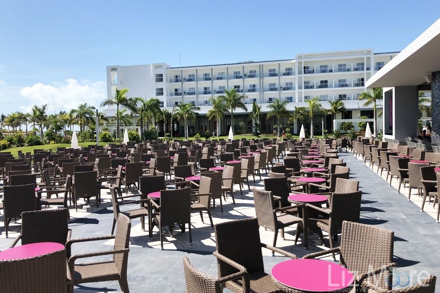large outside dining area with chairs and pink tables and room buildings in the background