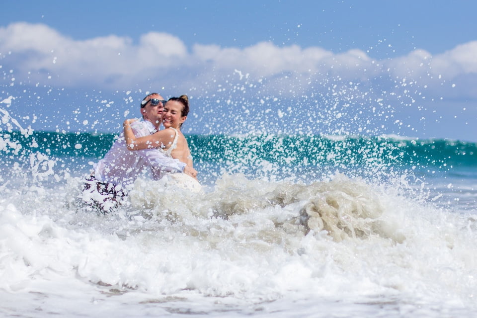 wedding couple splashing around in the beach at the ocean