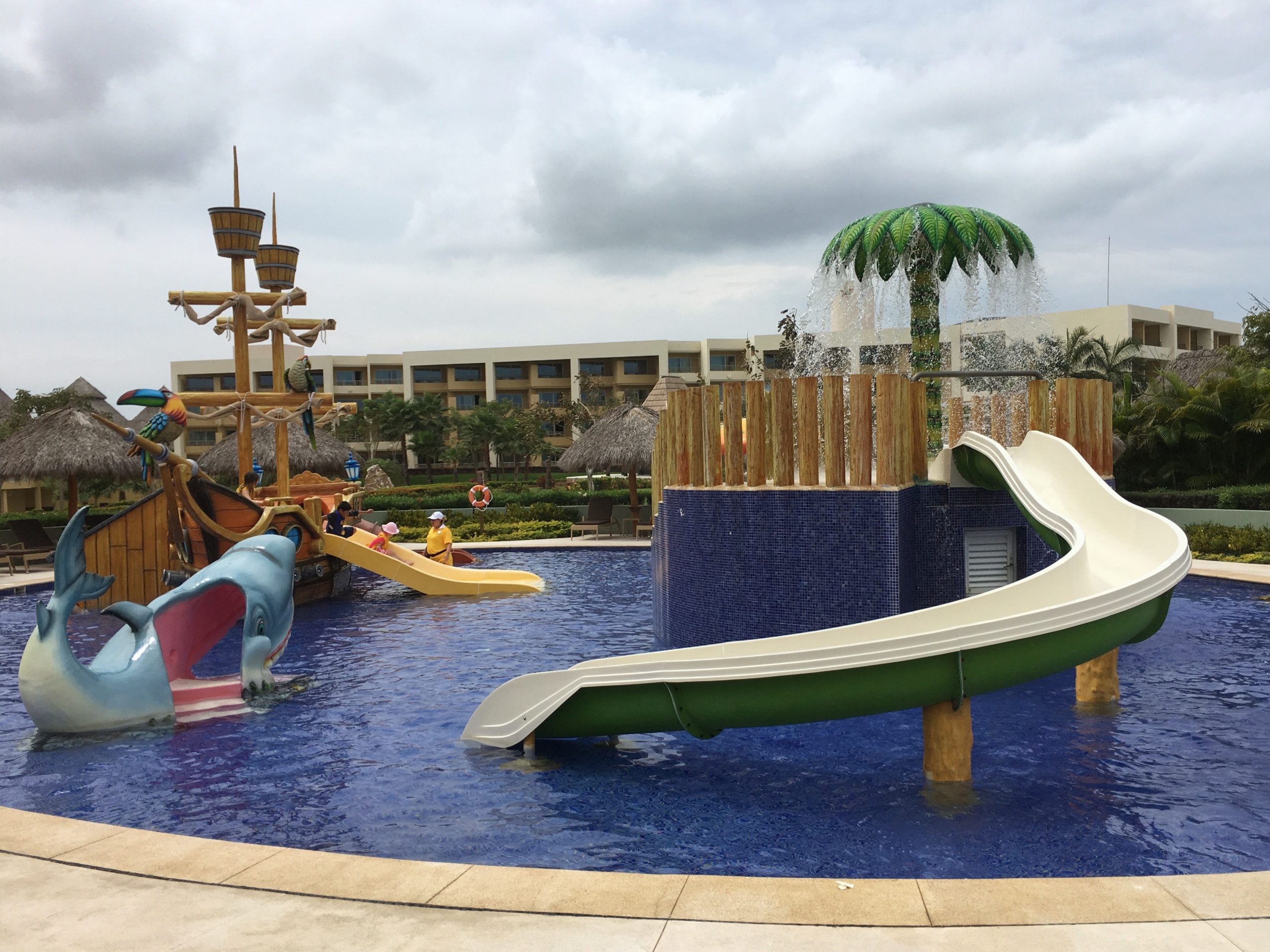 children's water play area with Palm tree and room buildings in the background