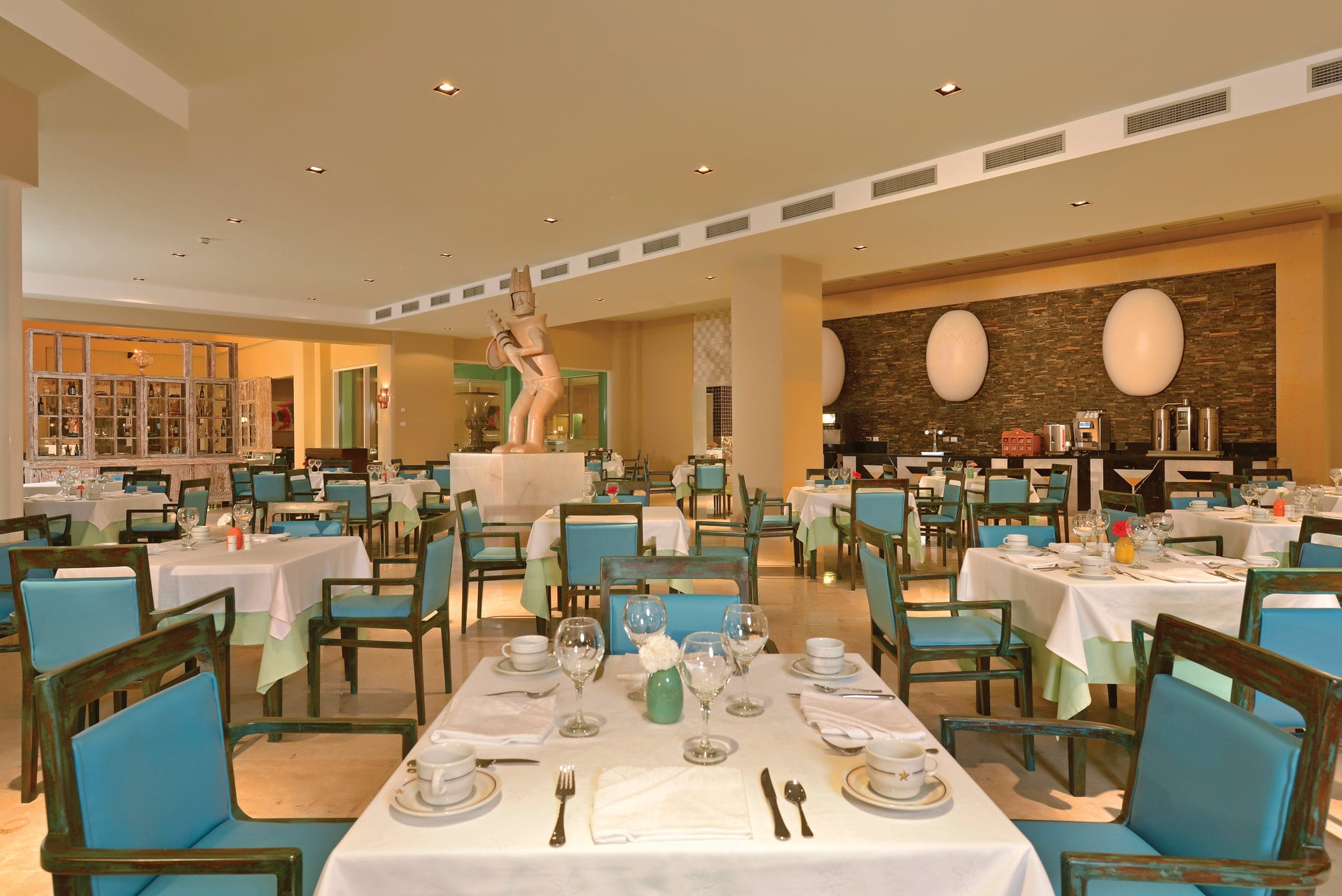 main buffet restaurant in the evening with a blue leather chairs white table linens and statue