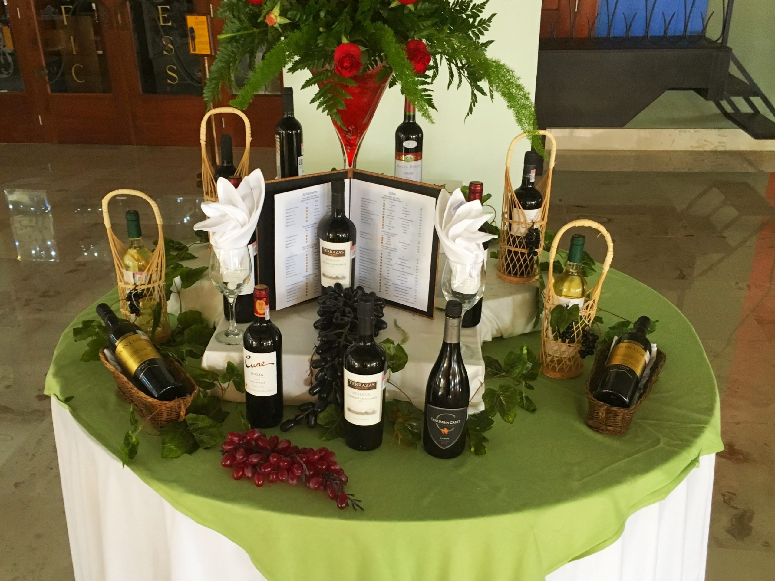 assortment of different premium wines on a green table in the main dining room restaurant area