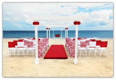 Beach ceremony with a red and white Decor and red carpet going up to the gazebo